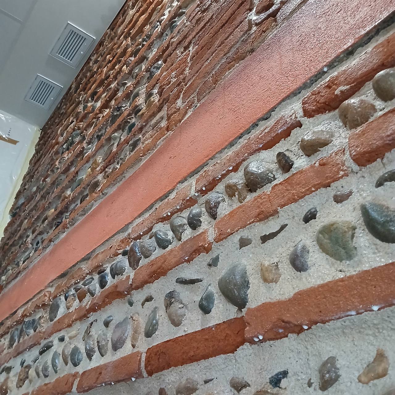 Mur briques foraine traité avec VMC en partie haute — pièce habitable terminée